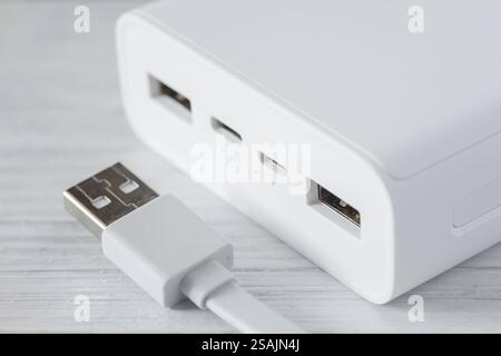 Nahaufnahme einer weißen Powerbank mit mehreren usb-Anschlüssen, einer mit eingestecktem Kabel. Ladegeräte mit Hilfe einer Powerbank. Stockfoto