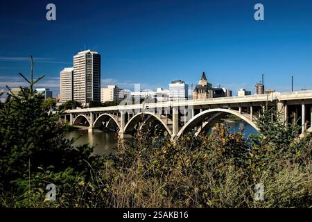 Eine Brücke über einen Fluss mit einer Stadt im Hintergrund. Die Brücke besteht aus Beton. Die Stadt ist voller hoher Gebäude Stockfoto