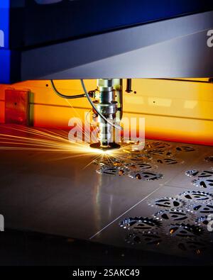 Der Laser-Schneidkopf erzeugt Funken, wenn er Formen in ein Metallblech schneidet, was Präzisionstechnik und industrielle Automatisierung zum Vorschein bringt Stockfoto