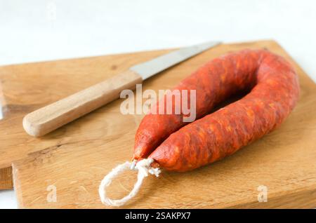 Spanische Chorizo-Wurst mit rotem Pfeffer, Paprika und Knoblauch auf einem hölzernen Schneidebrett mit einem Messer. Traditionelle mediterrane Küche. Horizontal Stockfoto