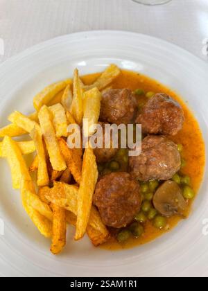 Fleischbällchen mit Erbsen und gebratenen Kartoffeln. Spanien. Stockfoto