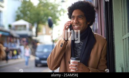 Stilvoller Junger Mann Mit Takeaway Kaffee Macht Telefonanruf Auf Der Stadtstraße Mit Handy Stockfoto
