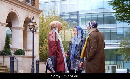 Gruppe Junger Britisch-Muslimischer Geschäftsfrauen, Die Sich Außerhalb Des Büros Treffen Und Unterhalten Stockfoto
