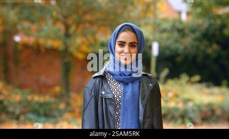 Kopf Und Schultern Porträt Der Lächelnden Jungen Britischen Musliminnen, Die Hijab Im Autumn Park Tragen Stockfoto