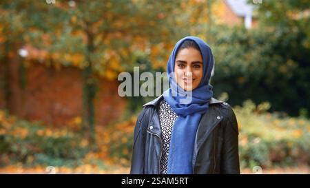 Kopf Und Schultern Porträt Der Lächelnden Jungen Britischen Musliminnen, Die Hijab Im Autumn Park Tragen Stockfoto