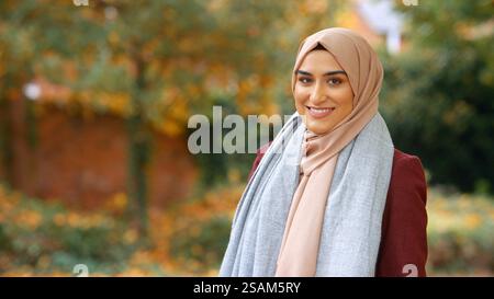 Kopf Und Schultern Porträt Der Lächelnden Jungen Britischen Musliminnen, Die Hijab Im Autumn Park Tragen Stockfoto