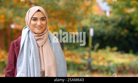 Kopf Und Schultern Porträt Der Lächelnden Jungen Britischen Musliminnen, Die Hijab Im Autumn Park Tragen Stockfoto