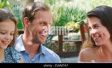 Rückansicht Der Liebevollen Familie, Die Auf Einem Holzsteg Am See Sitzt Stockfoto