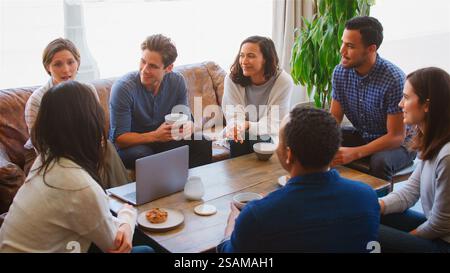 Gruppe Von Geschäftsleuten, Die Am Laptop Arbeiten, Sitzen Auf Sofas Im Café Und Treffen Sich Informell Stockfoto