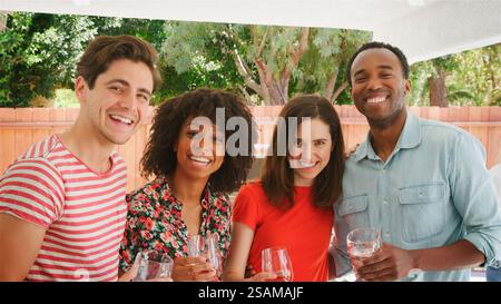 Porträt Einer Gruppe Lächelnder Junger Freunde, Die Sommergetränke Im Freien Im Garten Zu Hause Genießen Stockfoto