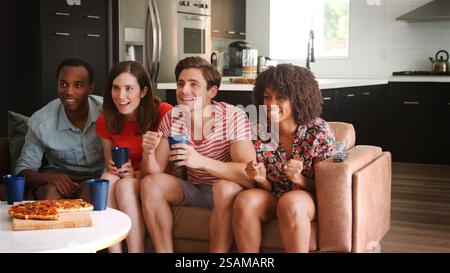 Angespannte und begeisterte Gruppe junger Freunde zu Hause, die gemeinsam Sport im Fernsehen sehen Stockfoto