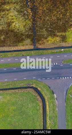 Aus der Vogelperspektive auf eine ländliche Gegend mit einer geraden Straße mit markierten Gassen, umgeben von grünem Gras, einem kleinen Kanal und Feuchtgebieten. Der lebendige Stockfoto