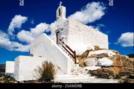 Eine malerische weiße Kapelle auf einem felsigen Hügel mit einer Treppe, die zum Eingang führt. Der Himmel ist hellblau mit flauschigen weißen Wolken Stockfoto
