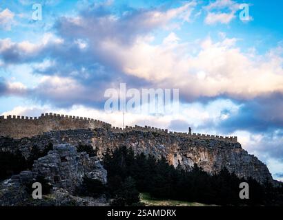 Ein historisches Schloss auf einer felsigen Klippe, umgeben von üppigem Grün und dramatischen Wolken am Himmel. Die Steinmauern sind gut erhalten und eindrucksvoll Stockfoto
