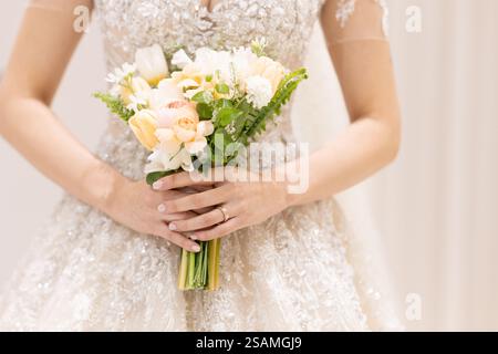 Die Frau hält einen Blumenstrauß in der Hand. Der Blumenstrauß besteht aus gelben Blüten Stockfoto