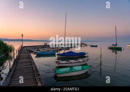 Ruhiges idyllisches Bild von Booten neben dem Pier bei Sonnenuntergang in Balatonlelle am Balaton. Stockfoto