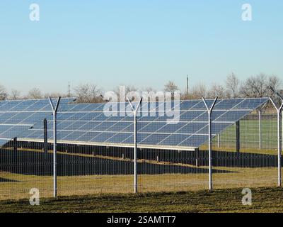 Solarbatterie in der Struktur des Energiespeichers hinter transparentem Zaun am sonnigen Tag, Sammlung von Solarenergie durch große Paneele auf dem Bauernhof Stockfoto