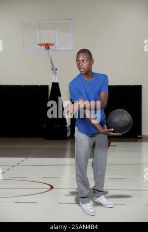 Schöner junger schwarzer afroamerikanischer Teenager, der Basketball spielt Stockfoto