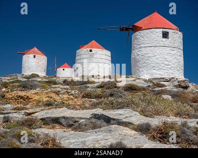 Vier Windmühlen gegen einen tiefblauen Himmel: Vier der Windmühlen, die sich in bösartigen verfallszuständen auf dem felsigen Kamm oberhalb von Chora befinden, Amorgos gegen einen tiefblauen Himmel. Stockfoto