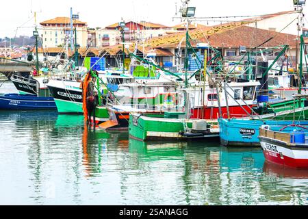 Eine lebhafte Szene im Hafen von Saint-Jean-de-Luz, Frankreich, mit farbenfrohen Fischerbooten, die in der Nähe des Hafens anlegen. Stockfoto