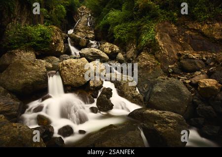 Ein kaskadenförmiger Wasserfall, der über moosige Felsen fließt, umgeben von üppigem Grün, schafft eine ruhige und ruhige natürliche Szene. Ghunji Wasserfälle, Georgia. Stockfoto