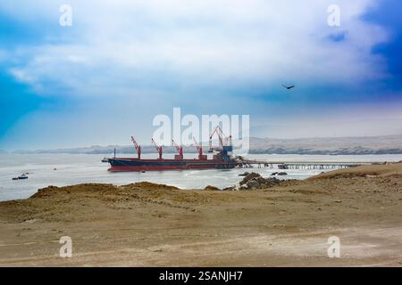 Ein Frachtschiff, das in einem Hafen an der Küste der Atacamawüste in Chile mit Kupferkonzentrat beladen wird. Stockfoto