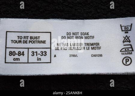 Etikett mit Waschanweisungen im Pullover – Symbole und Anweisungen zum Waschen der Pflege in Englisch und Französisch Stockfoto
