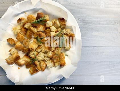 Hausgemachte gewürzte Croutons auf einem Teller auf einem hellgrauen hölzernen Hintergrund. Direkt darüber. Stockfoto