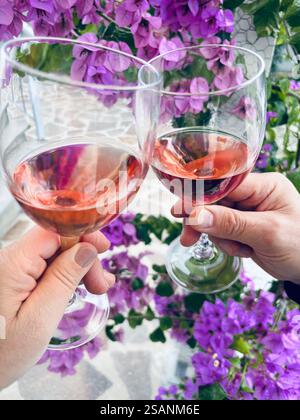 Ein paar, das draußen mit Gläsern Rosenwein toast. Romantische und feierliche Beziehungen. Stockfoto