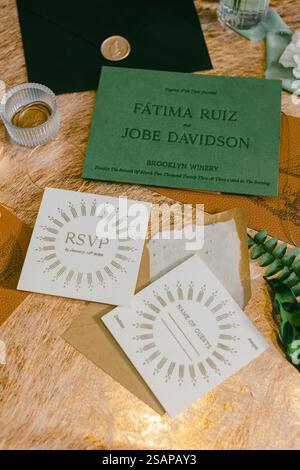 Farbenfrohe Hochzeitseinladungen sind wunderschön auf einem dekorativen Tisch angeordnet. Die Schreibwaren verfügen über elegante Schriftzüge und einzigartige Designs, die ideal für einen geeignet sind Stockfoto