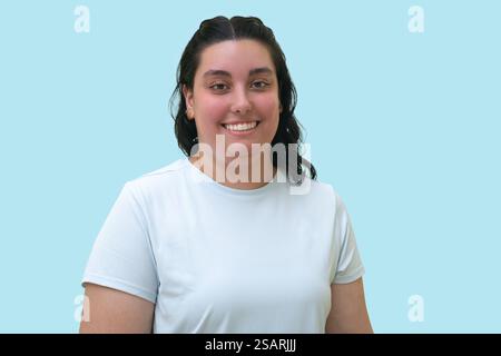 Lächelnde junge Frau im Sport-T-Shirt auf hellblauem Hintergrund. Stockfoto