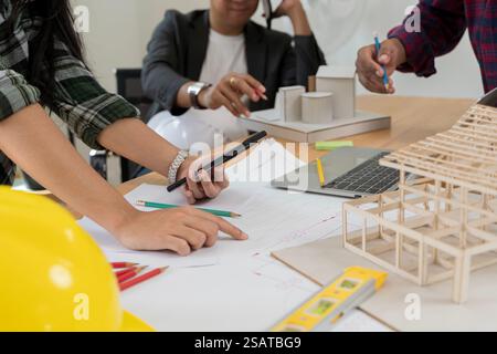 Architekt erklärt den Projektplan den Kunden. Daten funktionieren und Tablet-Notebook. Selbstbewusste Geschäftsfrau mit Architekturmodell im Büro. Stockfoto