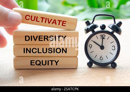 Pflegen Sie Text für Vielfalt, Einbeziehung und Gerechtigkeit auf Holzblöcken mit Tischuhr. D- und I-Konzept. Stockfoto