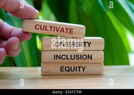 Handplatzierung Kultivieren Sie Diversity, Inklusion und Equity Holztext mit verschwommenem Naturhintergrund. Stockfoto