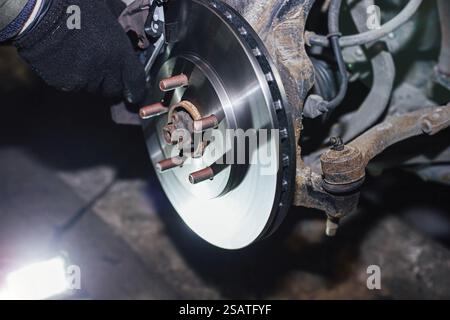 Mechaniker, der eine Autobremsscheibe mit Schwerpunkt auf rostfreien Bauteilen und metallischen Texturen überprüft Stockfoto
