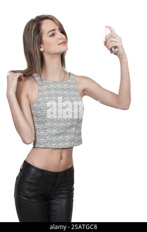 Schöne Frau, die Parfüm aufträgt, indem sie aus einer Flasche spritzt Stockfoto