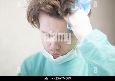 Ein Doktor in blauen Peelings, der frustriert mit Hand an Kopf aussieht Stockfoto