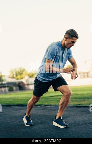 Läufer überprüft Smartwatch während des Trainings auf einem Lauffeld in der Nachmittagssonne auf Tempo Stockfoto