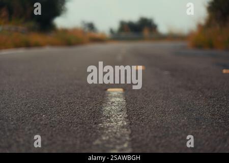 Eine Nahperspektive einer leeren Asphaltstraße, die sich in die Ferne zieht und eine Reise oder einen Weg nach vorn symbolisiert. Stockfoto
