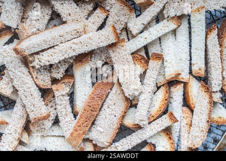 Hintergrund mit der Textur von Brotscheiben, die auf einem Drahtgestell getrocknet wurden. Nahaufnahme von Crackern oder Croutons. Hochwertige Fotos Stockfoto