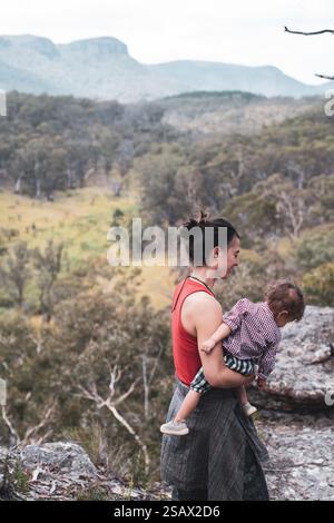 Glückliche gesunde Mutter hält Baby Kleinkind auf einem Spaziergang in der schönen Natur Stockfoto