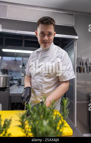 Koch bereitet Zutaten in der professionellen Küche zu Stockfoto