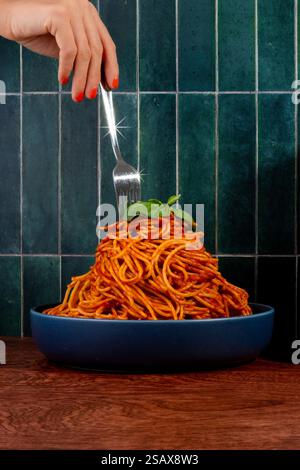 Eine Gabel, die einen Turm aus Spaghetti-Pasta und Tomatensauce durchsticht Stockfoto