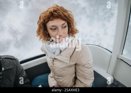 Junge Frau, die eine ruhige Winterfahrt in einer Gondelkabine genießt Stockfoto