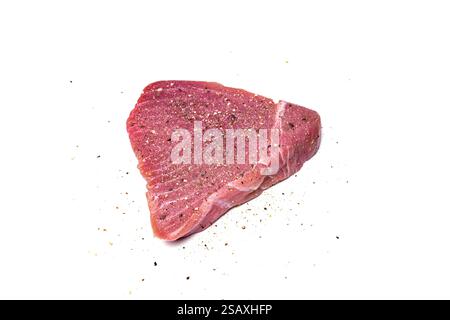 Rohes, in Scheiben geschnittenes Thunfischsteak mit Salz und grobem Pfeffer, isoliert auf weiß. Draufsicht, Nahaufnahme, keine Leute. Stockfoto