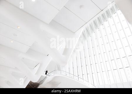 Ein grafisches, helles weißes Interieur des Westfield Shopping Mall im World Trade Center, NYC, das eine Einzelfigur auf einem entfernten Balkon umrahmt. Stockfoto