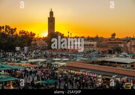 Geschäftige Marktstände am Jemaa el-Fnaa Platz bei Sonnenuntergang, Koutoubia Moschee im Hintergrund in der Medina, Marrakesch, Marokko. Stockfoto