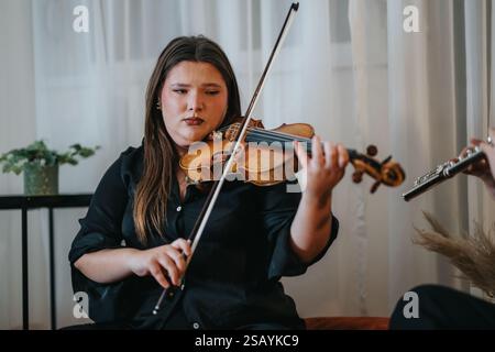 Eine junge Frau, die im Rahmen einer musikalischen Aufführung im Haus Geige spielt Stockfoto