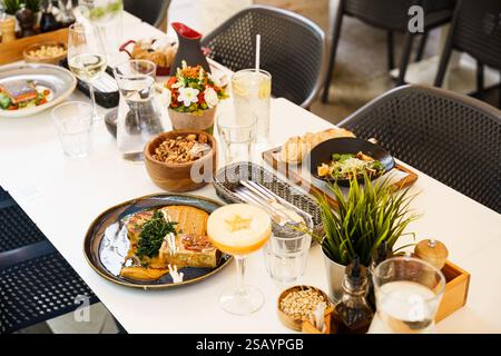 Ein wunderschön gestalteter Brunch-Tisch im Freien mit einer Vielzahl von Gerichten und Getränken, einschließlich Salaten, Suppen, frischen Säften und Vorspeisen. Die Stockfoto