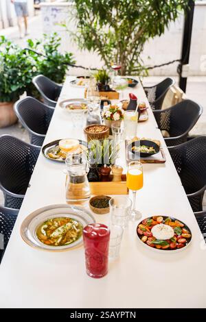 Ein wunderschön gestalteter Brunch-Tisch im Freien mit einer Vielzahl von Gerichten und Getränken, einschließlich Salaten, Suppen, frischen Säften und Vorspeisen. Die Stockfoto